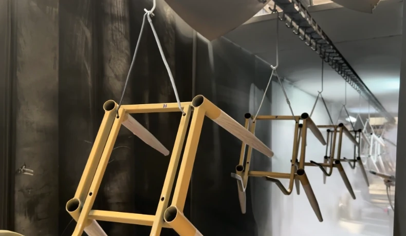 Gold chair frames hanging on a powder-coating conveyor line